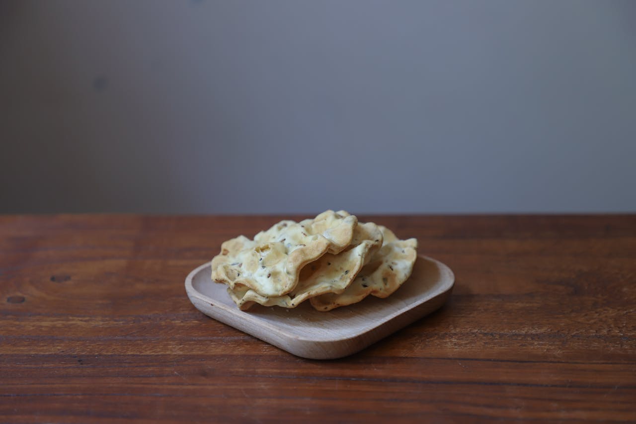 A stack of homemade crackers on a wooden plate, perfect for a rustic snack or appetizer.