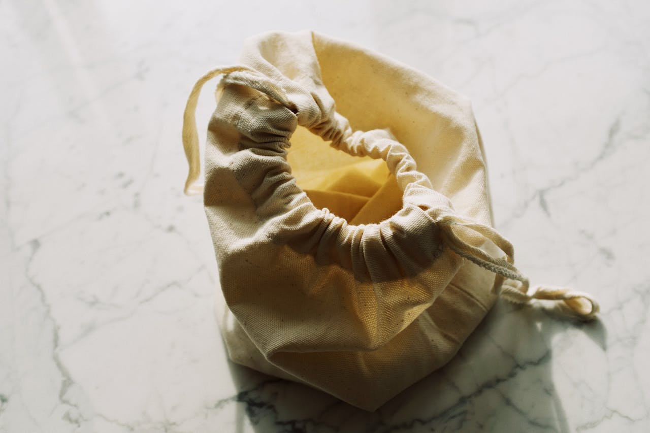 From above view of small zero waste textile bag with drawstrings placed on white marble table in light room