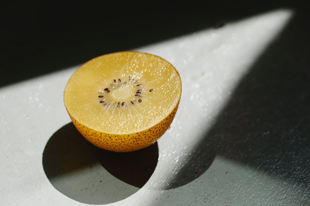 A sunlit close-up of a fresh golden kiwi half, showcasing its juicy texture and vibrant seeds.